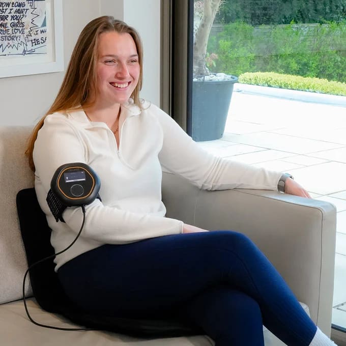 Woman relaxing at home with Celler8 PEMF on her arm