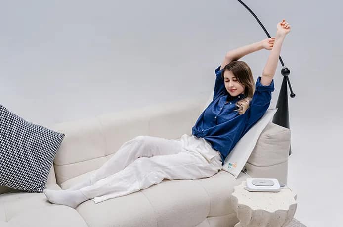 Relaxing with high-coil PEMF therapy pad for lower back relief on couch