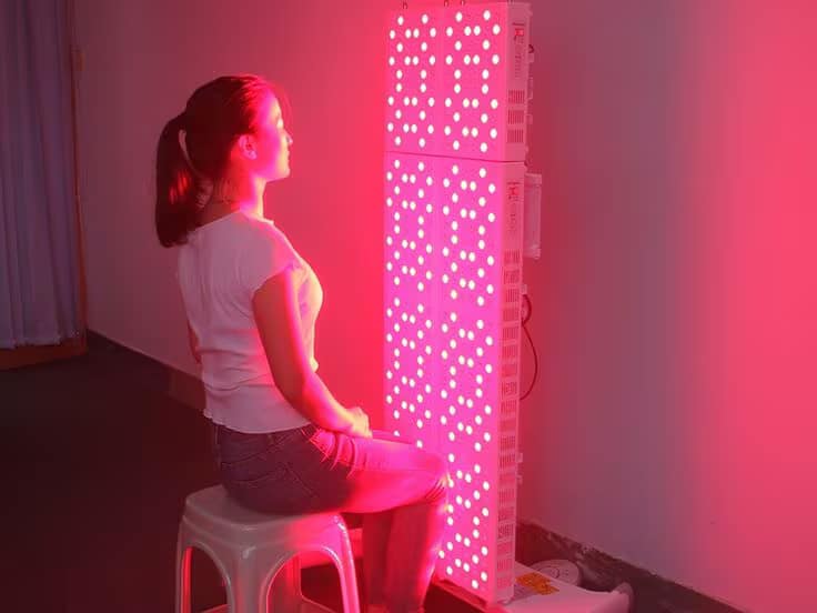 Donna che riceve trattamento terapia con luce rossa con Pannello ApeBorn Elite a Corpo Intero a casa