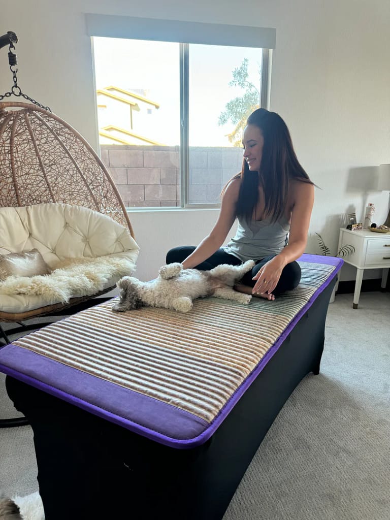 Woman relaxing on PEMF therapy mat with her dog during a home session