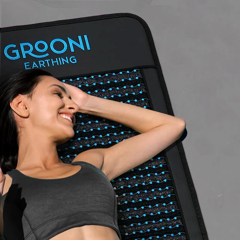Woman enjoying relaxation on Grooni PEMF mat with infrared therapy