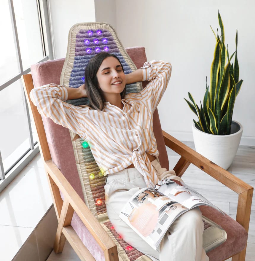 Young woman enjoying chakra balancing benefits on HealthyLine Rainbow Chakra PEMF Chair Mat