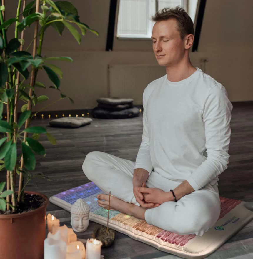 Man meditating on HealthyLine Rainbow Chakra PEMF MiniMat for energy alignment and relaxation