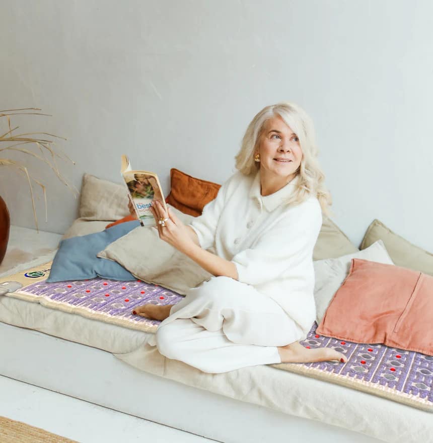 Donna anziana che legge un libro mentre è comodamente seduta sul Materassino HealthyLine TAJ