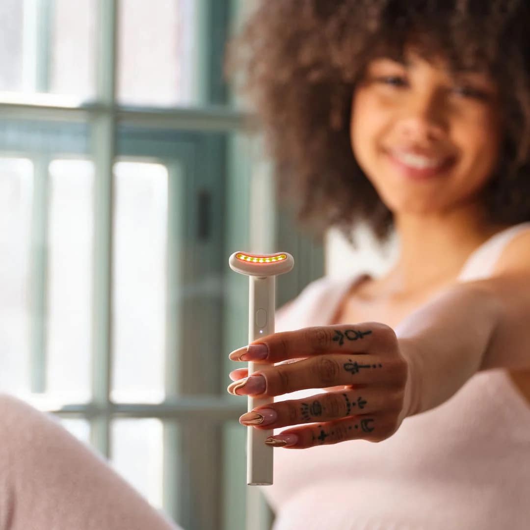 Woman displaying Kala Red Light Therapy Wand handheld portable LED facial treatment tool