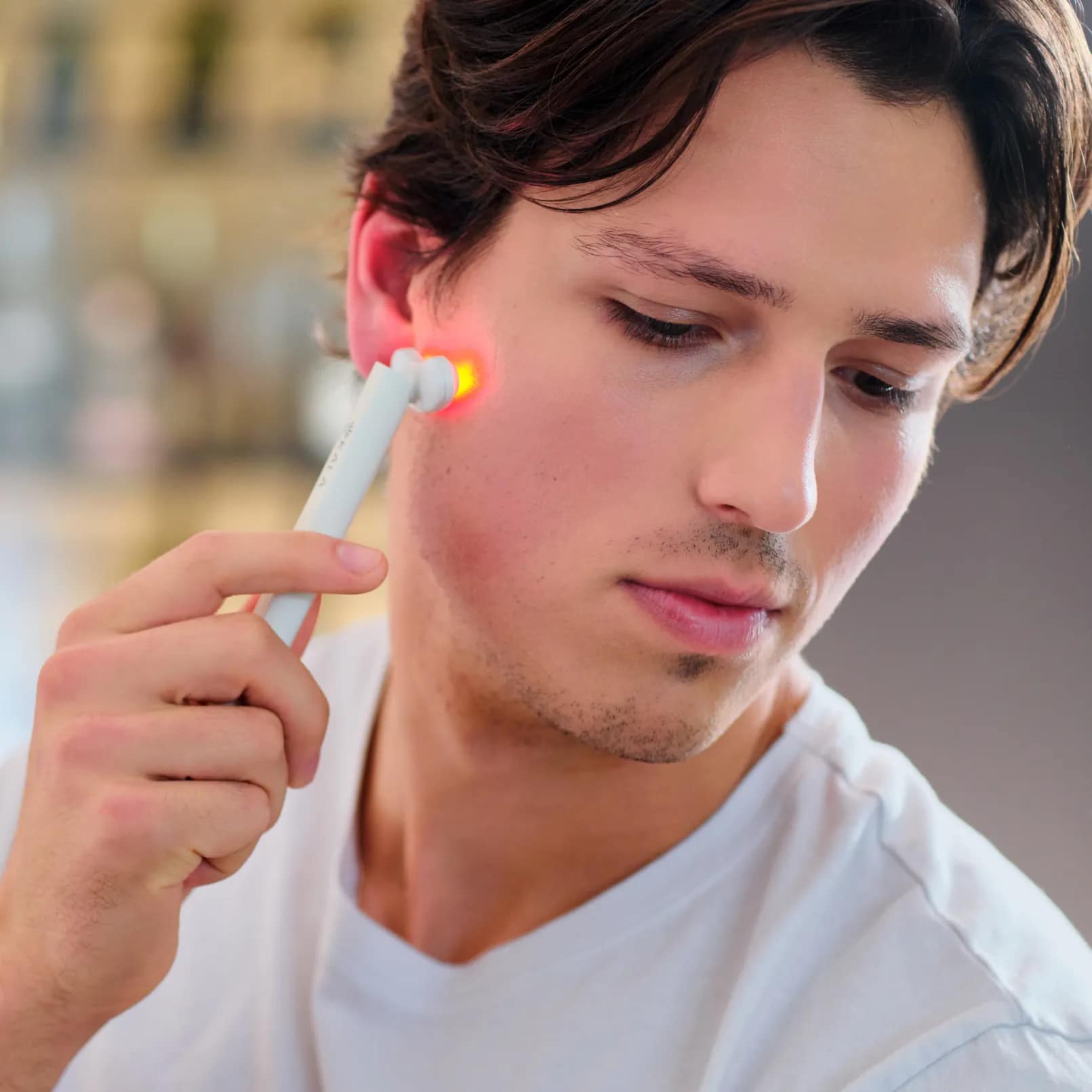 Man applying Kala LED Wand to face for precision handheld red light therapy treatment