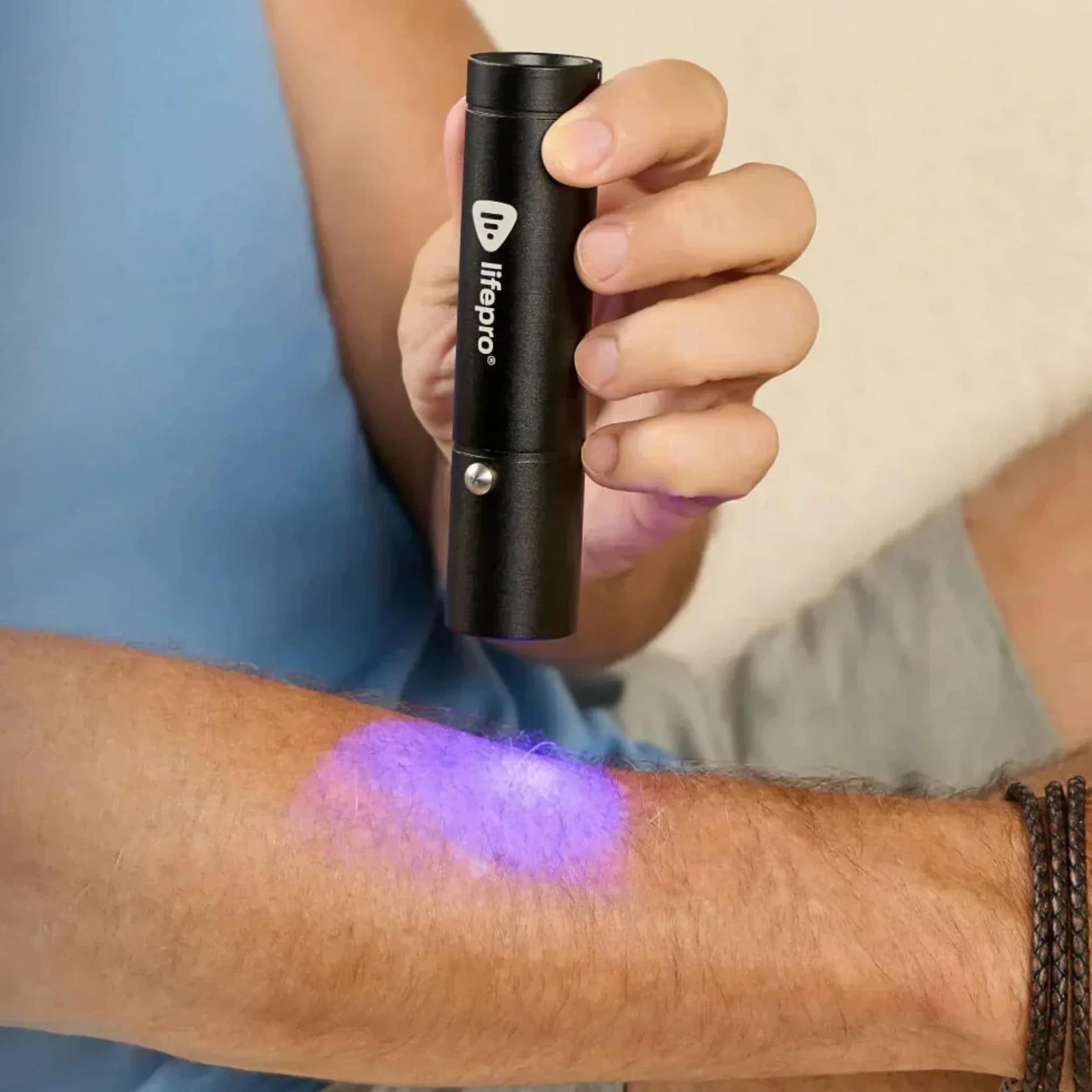Man using LifePro Red Light Torch on arm with purple wavelength for combination LED therapy session