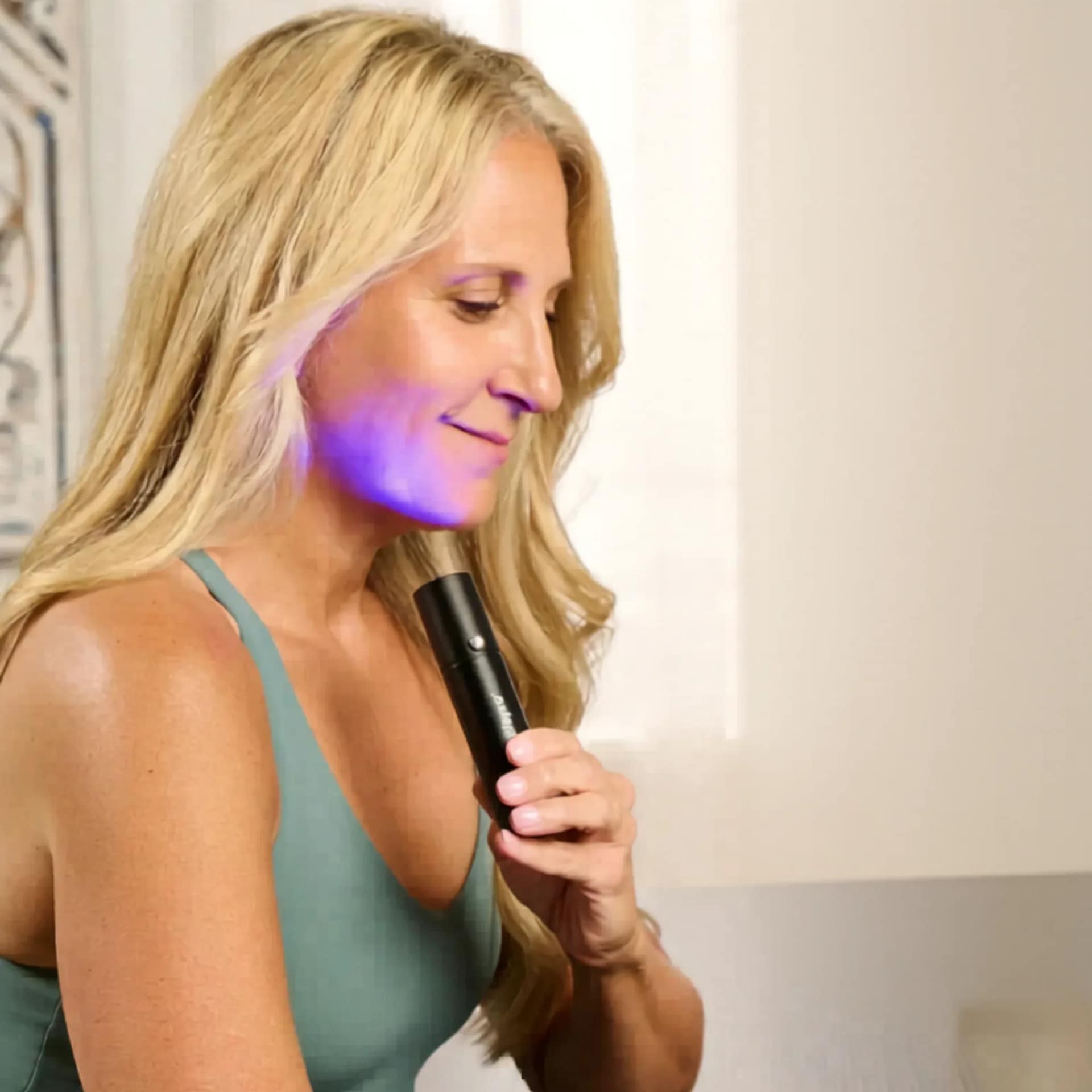 Woman treating lower cheek with LifePro Lumicure Red Light Therapy Torch in purple LED mode for facial therapy