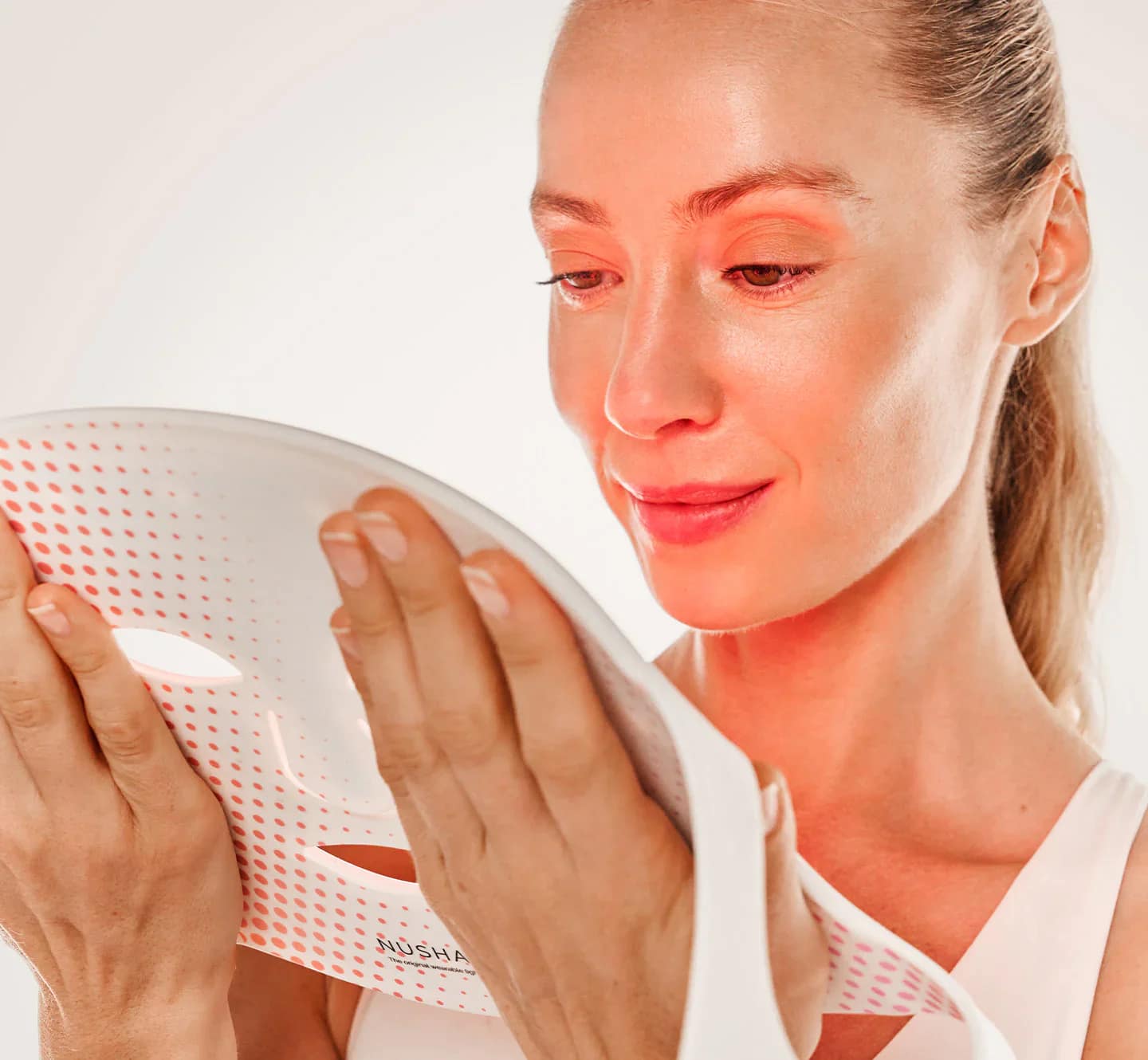 Woman preparing Nushape Red Light Face Mask for at-home phototherapy treatment