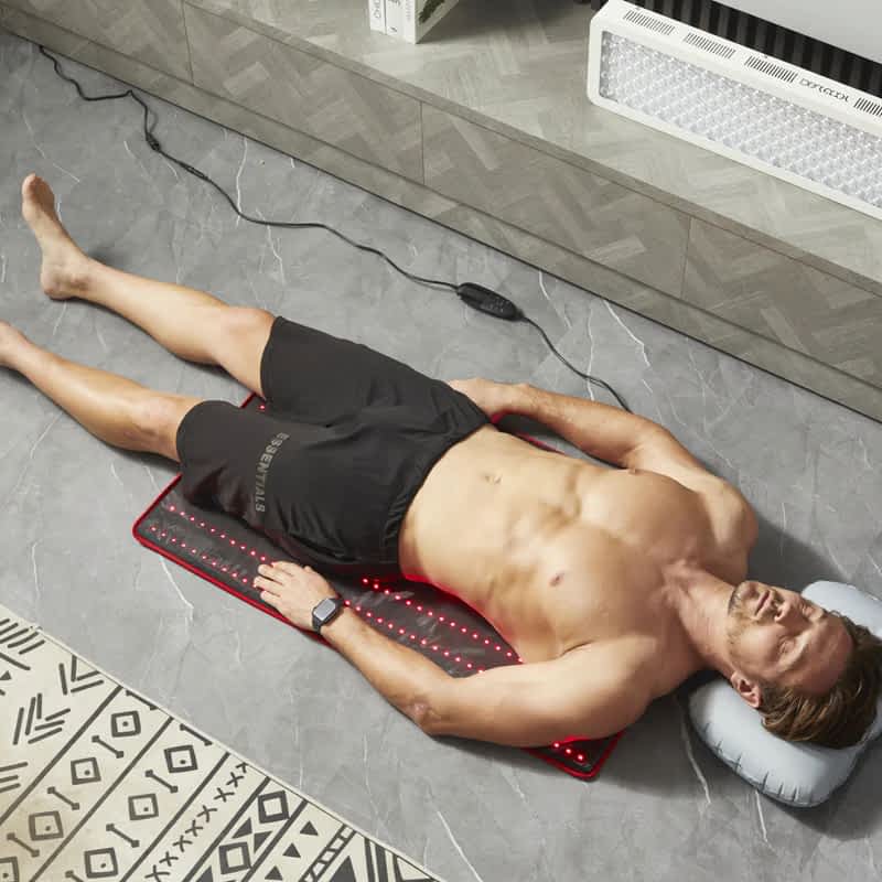 Man using BestQool LED Mat with included inflatable pillow for enhanced comfort during therapy